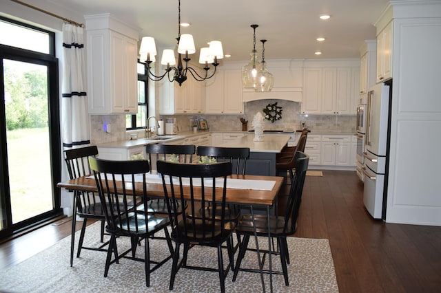 dining space with dark hardwood / wood-style floors, a wealth of natural light, a notable chandelier, and sink