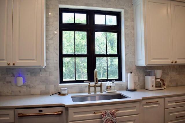 kitchen featuring dishwashing machine, white cabinetry, sink, and a wealth of natural light