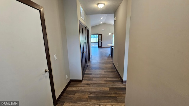 corridor with dark hardwood / wood-style flooring and vaulted ceiling