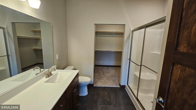 bathroom featuring vanity, a shower with door, and toilet