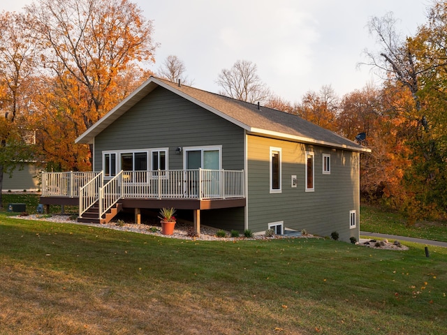 rear view of house featuring a wooden deck and a lawn