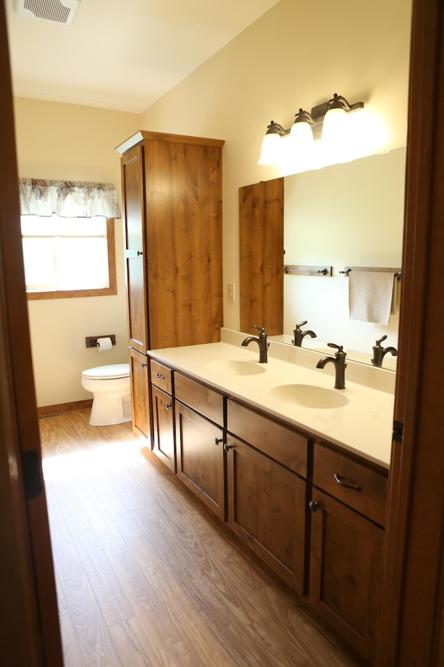 bathroom featuring hardwood / wood-style floors, double vanity, and toilet