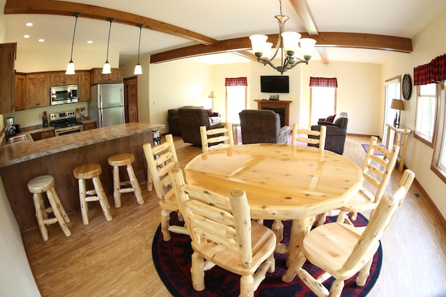 dining space featuring light hardwood / wood-style floors, a notable chandelier, beam ceiling, and a healthy amount of sunlight