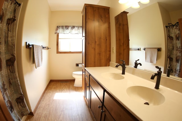 bathroom featuring hardwood / wood-style flooring, toilet, and double sink vanity