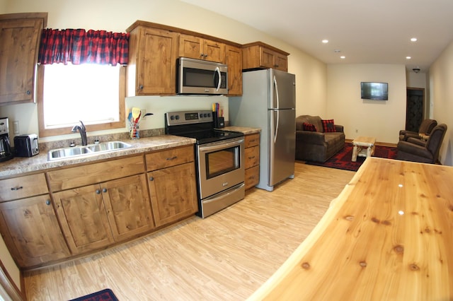 kitchen with light hardwood / wood-style floors, appliances with stainless steel finishes, and sink