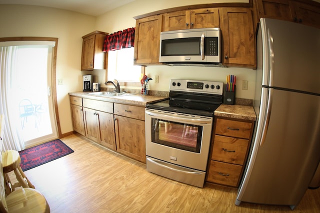 kitchen featuring sink, a wealth of natural light, light wood-type flooring, and stainless steel appliances