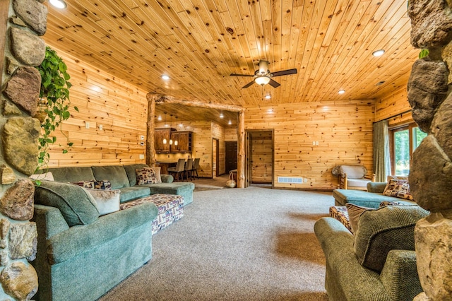 living area featuring visible vents, wood walls, wood ceiling, carpet floors, and a ceiling fan