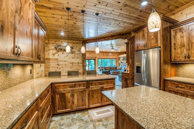 kitchen with brown cabinets, stone finish floor, a peninsula, wooden ceiling, and stainless steel fridge with ice dispenser