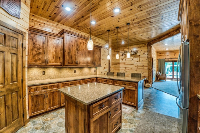 kitchen featuring a peninsula, wooden ceiling, stone flooring, and freestanding refrigerator