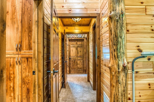 corridor with wooden ceiling, wooden walls, and carpet flooring