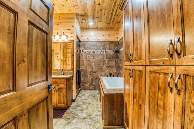 full bathroom with vanity, a whirlpool tub, stone finish floor, wood ceiling, and wood walls