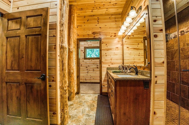 bathroom featuring a tile shower, wood walls, vanity, and stone finish flooring