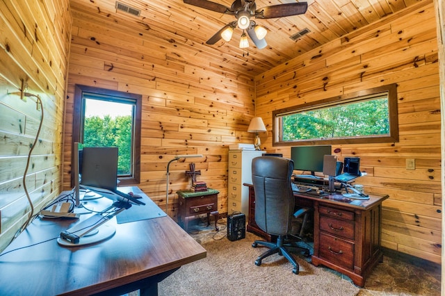 carpeted home office featuring wooden ceiling, wooden walls, a ceiling fan, and visible vents