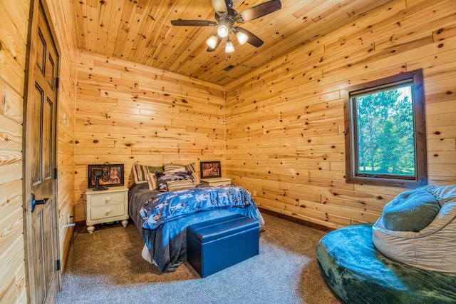 carpeted bedroom with ceiling fan, wooden ceiling, and wood walls