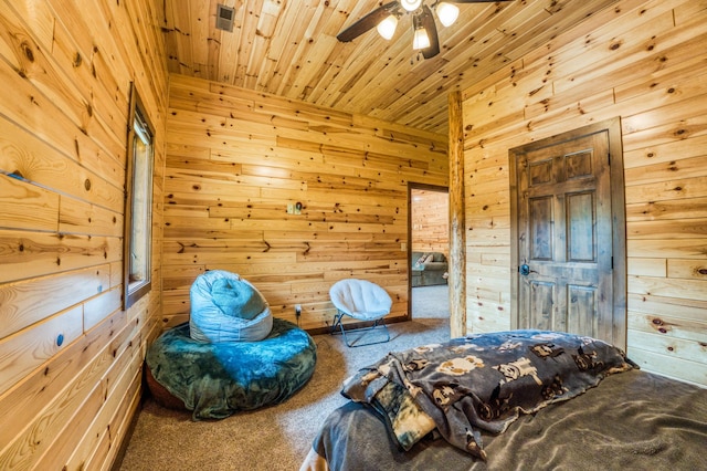 carpeted bedroom with ceiling fan, wood ceiling, and wood walls