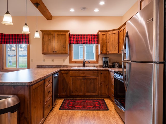 kitchen with light wood-type flooring, sink, appliances with stainless steel finishes, and kitchen peninsula