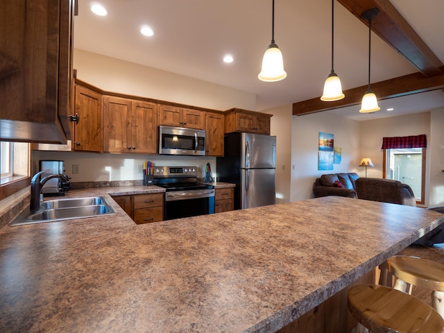 kitchen featuring kitchen peninsula, hanging light fixtures, appliances with stainless steel finishes, a kitchen breakfast bar, and sink