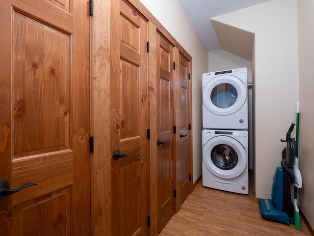 clothes washing area featuring stacked washer / dryer and light wood-type flooring