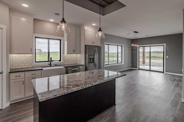 kitchen featuring a wealth of natural light, tasteful backsplash, refrigerator, and dark wood-type flooring