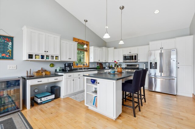 kitchen featuring wine cooler, white cabinetry, a kitchen island, light hardwood / wood-style flooring, and stainless steel appliances