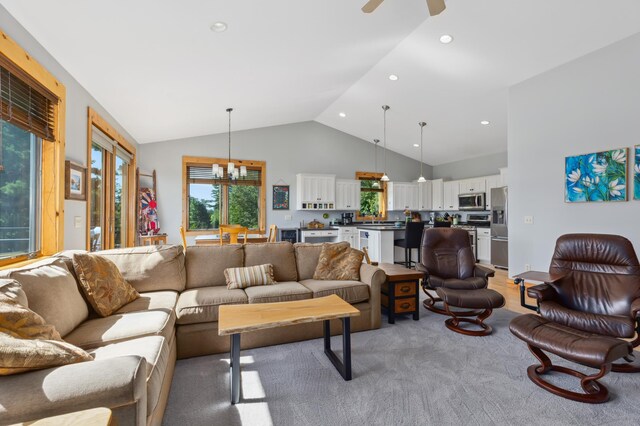 carpeted living room with ceiling fan with notable chandelier and lofted ceiling