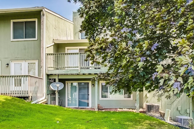 back of property featuring central air condition unit, a lawn, and a balcony