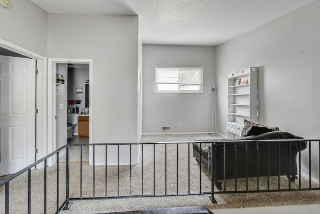 bedroom featuring a textured ceiling, ensuite bath, and carpet