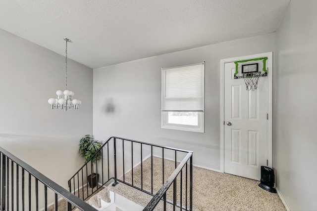 hallway featuring carpet, a textured ceiling, and a chandelier