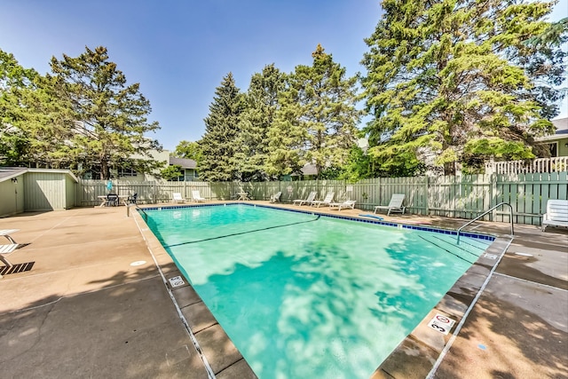 view of pool featuring a patio area and a storage unit