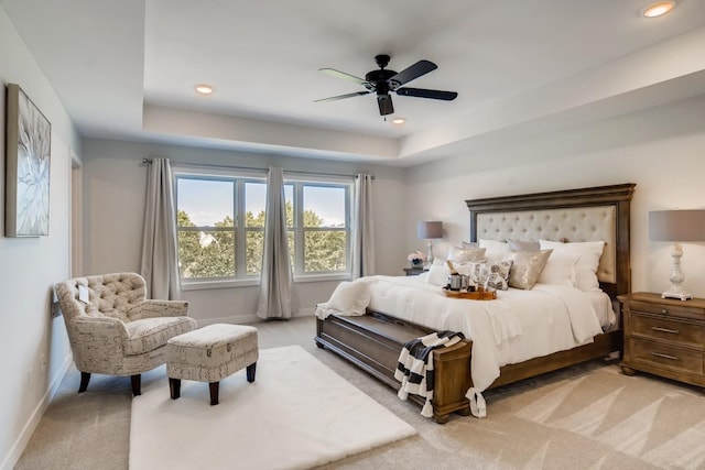 bedroom with ceiling fan, a raised ceiling, and light colored carpet