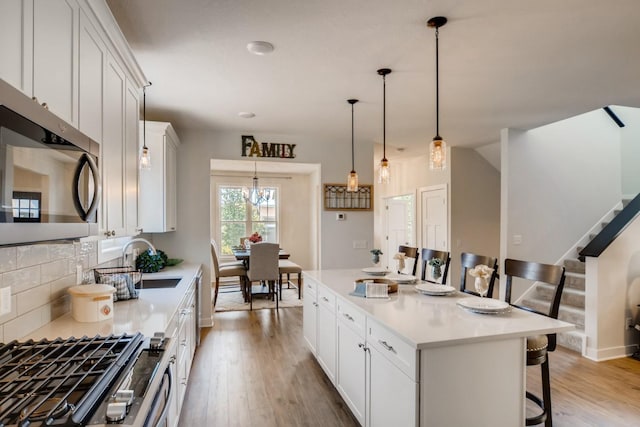 kitchen with backsplash, a kitchen island, stainless steel appliances, and light wood-type flooring