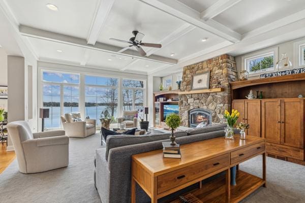 living room featuring beam ceiling, a fireplace, ceiling fan, light colored carpet, and coffered ceiling