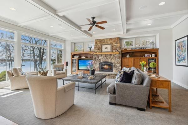 living room featuring beam ceiling, a stone fireplace, ceiling fan, carpet flooring, and coffered ceiling