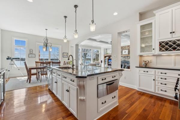 kitchen with a sink, glass insert cabinets, white cabinets, and dark wood-style flooring