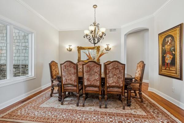 dining area with visible vents, arched walkways, wood finished floors, baseboards, and a notable chandelier