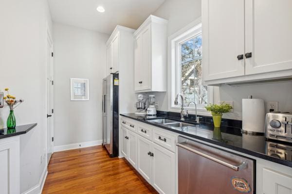 kitchen featuring a sink, white cabinets, dark countertops, and stainless steel appliances
