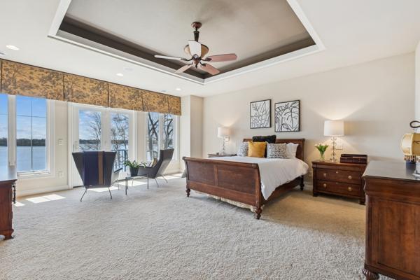 carpeted bedroom with a raised ceiling, access to outside, and ceiling fan