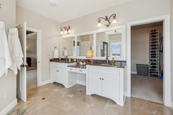 bathroom with baseboards, a walk in closet, tile patterned floors, and vanity