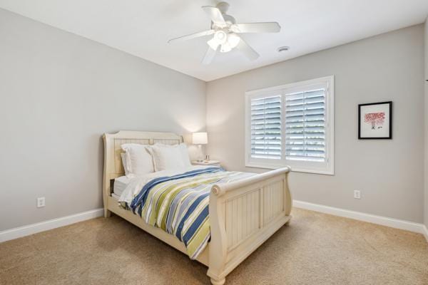 bedroom with light colored carpet, a ceiling fan, and baseboards