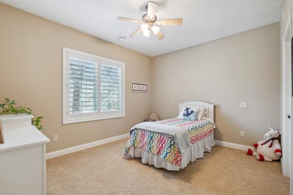 bedroom with a ceiling fan, baseboards, and light carpet