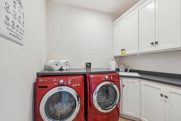 washroom with a sink, cabinet space, and independent washer and dryer
