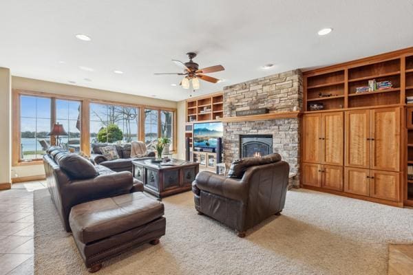 living area featuring a stone fireplace, recessed lighting, built in features, and ceiling fan