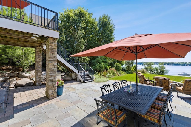 view of patio with stairs, outdoor dining area, an outdoor fire pit, and a water view