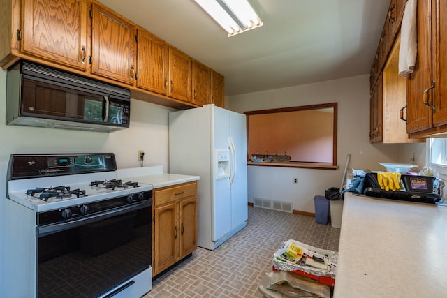 kitchen featuring gas range and white refrigerator with ice dispenser