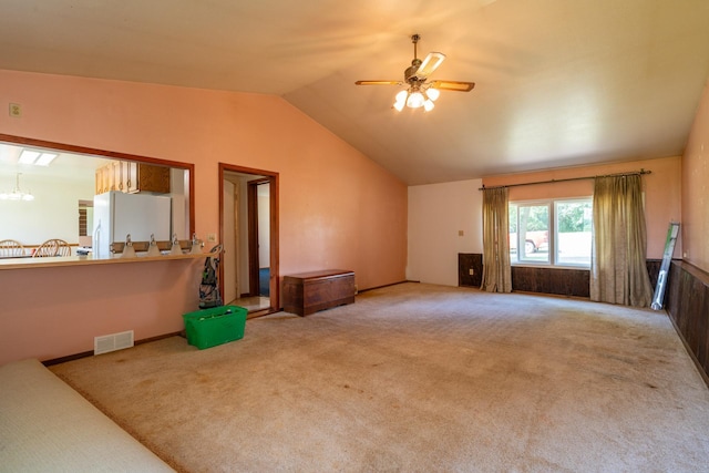 carpeted living room featuring lofted ceiling and ceiling fan with notable chandelier