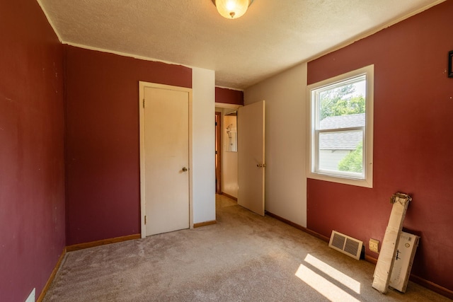 unfurnished bedroom with light colored carpet, a textured ceiling, and a closet