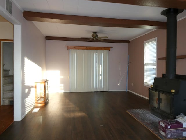 living room featuring beamed ceiling, a wood stove, hardwood / wood-style flooring, and ceiling fan