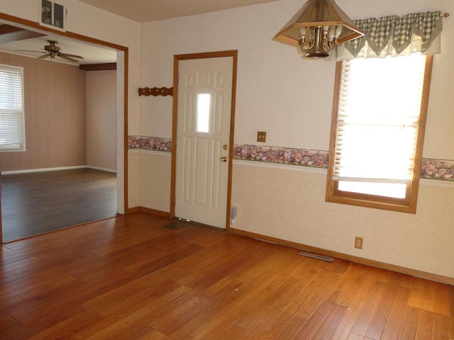 entryway featuring ceiling fan with notable chandelier and hardwood / wood-style floors