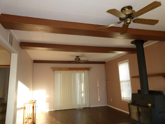 737 3rd Ave, Windom, MN 56101 - unfurnished living room featuring a wood stove, beamed ceiling, a ceiling fan, and wood finished floors