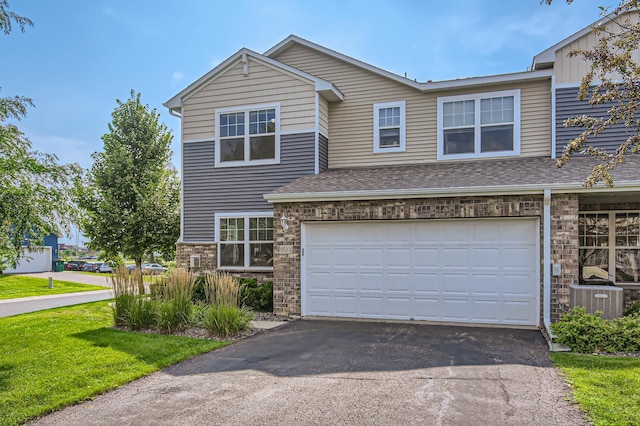 view of front of property with a front lawn, central AC unit, and a garage